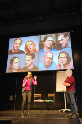 Ein Mann und eine Frau auf einer Bühne, die eine Applied Improv spielen