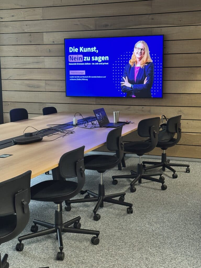 Bild von einem leeren Meetingraum mit angeschaltetem Bildschirm auf dem eine Präsentation gestartet wurde