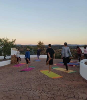 Männer und Frauen, die zum Sonnenaufgang Yoga miteinander machen