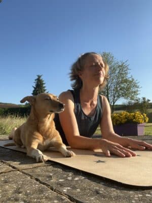 Frau und Hund gemeinsam in der Position der Sphinx auf der Yogamatte