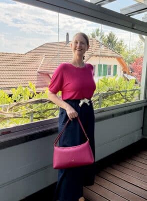 Blonde Frau mit pinkem Oberteil und pinker Tasche