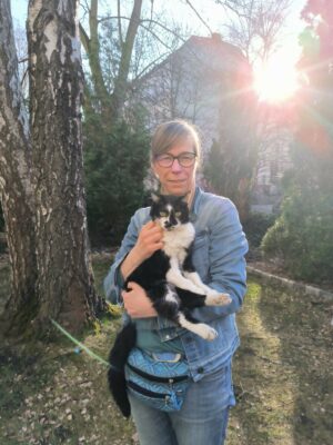 Frau mittleren Alters im Freien mit einem schwarz weissen Kater auf dem Arm