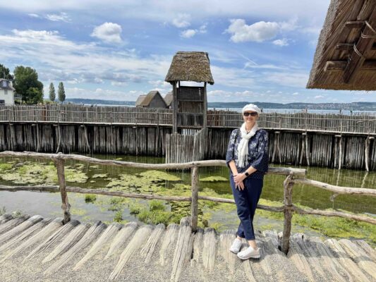 Frau, die vor den Pfahlbauten in Unteruhldingen am Bodensee steht