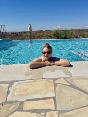Eine Frau mit Sonnenbrille und hochgesteckten Haaren in einem Swimmingpool