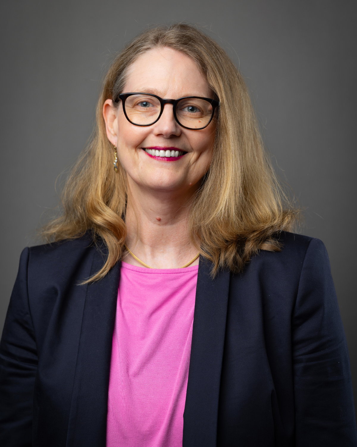 Lächelnde Frau mit blonden Haaren und Brille in Business Outfit